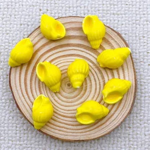 Macro shot of bright yellow conch shell beads for DIY jewelry making on wooden background