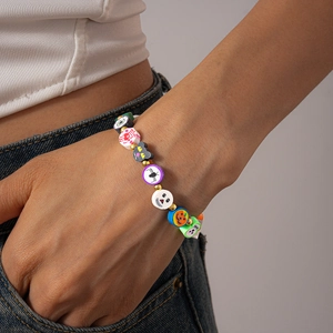 Close-up of Halloween beaded bracelet featuring clay pumpkin, ghost and cat charms on wrist