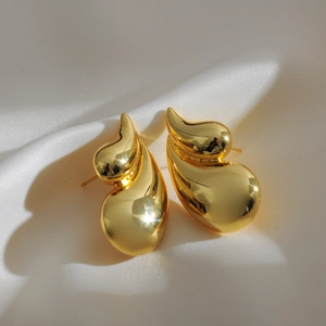 Close-up of 18K gold-plated double teardrop earrings on elegant white silk fabric