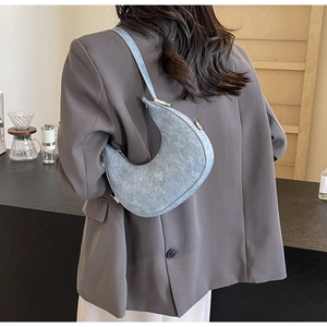 Detail view of crescent shoulder bag in matte grey-blue with adjustable strap on model