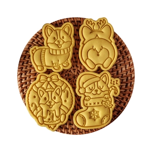 Christmas Corgi cookie cutters and golden embossed biscuits on a woven mat