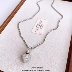 Elegant silver crown heart pendant necklace with zircon crystals on a textured tray