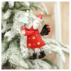 Detail of painted metal Santa ornament hanging on snowy Christmas tree branch
