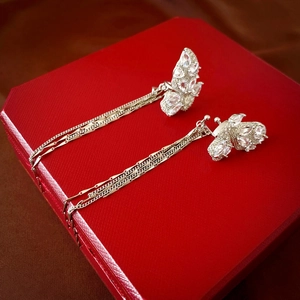 Gros plan de boucles d'oreilles papillon argentées avec zircons sur boîte rouge
