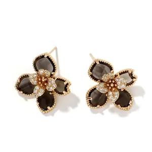 Détail de boucles d'oreilles fleurs avec pétales bruns, bordure dorée et zircons