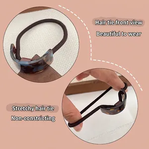 Tortoiseshell acetate hair tie with golden label and elastic rope on pink background