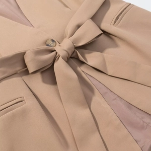 Close-up of khaki sleeveless suit vest detailing refined fabric texture and waist tie