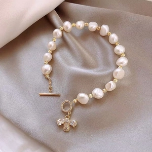 Baroque freshwater pearl bracelet with gold bee charm and toggle clasp on silk fabric