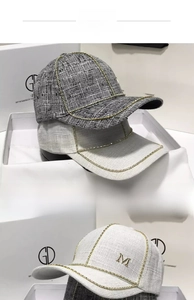 Detail of tweed baseball caps with rhinestone edges and metallic M logo in gift boxes