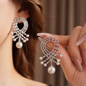 Vue détaillée de boucles d'oreilles pendantes argentées avec perles et zircons