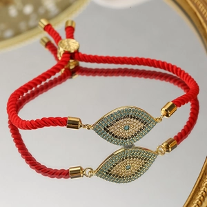 Adjustable red string bracelet with evil eye zircon pendant on a reflective mirror