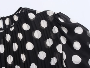 Detail of black and white polka dot chiffon dress with pleated fabric and puff sleeves