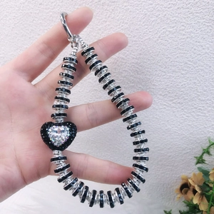 Detail shot of a beaded phone strap with a black heart pendant and sparkling center diamond