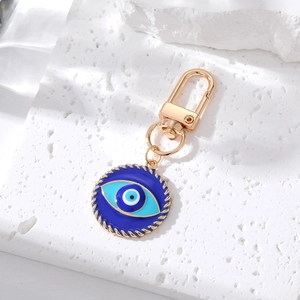 Detail of blue evil eye keychain with gold twisted frame on white stone plate