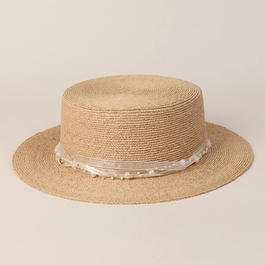 Close-up of natural raffia boater hat with elegant organza ribbon and pearl embellishments