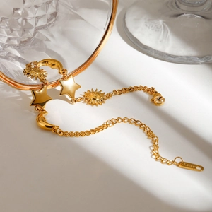 Detailed macro of gold celestial charms featuring sun, moon, and stars on stainless steel