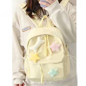 Detail of a pastel yellow backpack with cute plush star and bone charms on canvas fabric