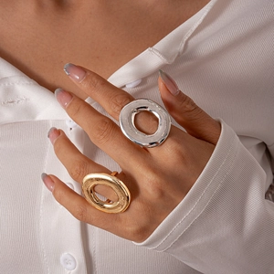 Detail of chunky hollow oval rings in gold and silver with textured lava finish on hand