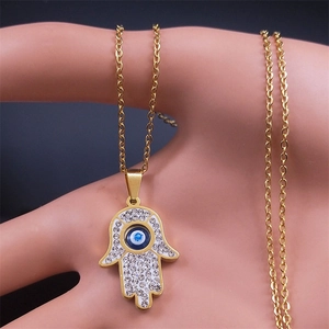 Close-up of golden Hamsa Hand pendant with sparkling crystals and Evil Eye motif