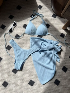 Macro detail of light blue bikini textured fabric with a matching tie sarong skirt
