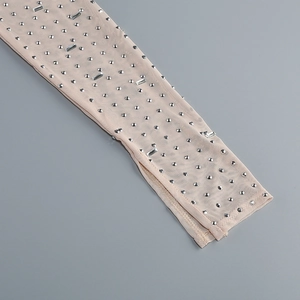 Detail shot of sheer mesh fabric with sparkling silver rhinestones on a nude garment