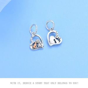 Detailed view of silver heart charm with gold cat and girl silhouette and white crystals