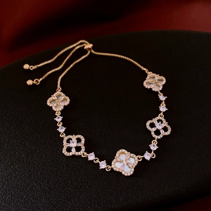 Detail view of adjustable gold four-leaf clover bracelet with mother of pearl and zircons