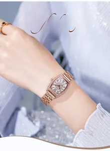 Gros plan d'une montre tonneau en or rose avec cadran en strass et chiffres arabes