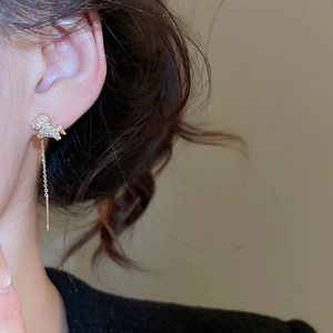Close-up of gold plated unicorn earrings with cubic zirconia stones worn by a model