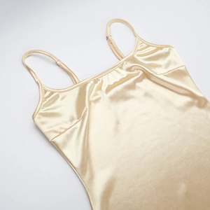 Detailed close-up of champagne satin fabric with adjustable spaghetti straps and silky texture
