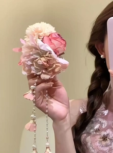 Nahaufnahme einer rosa Stoffblumen-Haarspange mit eleganten langen Perlenquasten und Blüten