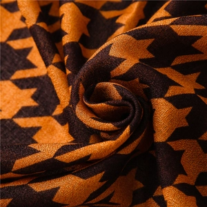 Detailed macro shot showing the soft woven texture of the orange and black houndstooth scarf