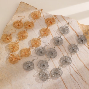 Detail of woven spiral metal jewelry set in gold and silver finish on marble background