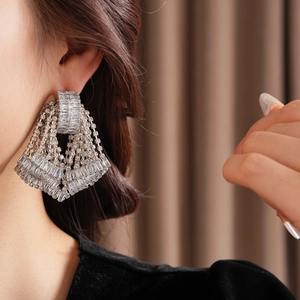 Close-up of model wearing silver tassel earrings with tiered crystal fringe detail