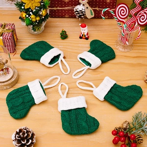 Set of 5 green knitted mini Christmas socks hanging ornaments on a festive wooden surface