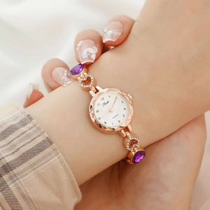Detail of rose gold quartz watch with purple gemstones and heart-shaped strap charms