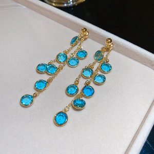 Dettaglio ravvicinato degli orecchini a nappa placcati oro 18k con perline di vetro blu