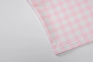 Gros plan du tissu vichy rose et blanc avec des coutures précises sur l'ourlet du haut