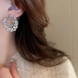 Élégantes boucles d'oreilles argentées avec perles et strass portées par un mannequin