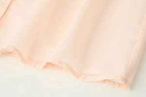 Gros plan détaillé de la couture de l'ourlet et du tissu en mousseline légère pêche
