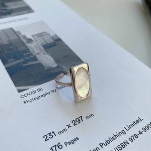 Macro detail of 925 silver adjustable ring with oval white shell inlay on minimalist book