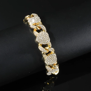 Détail macro d'un bracelet à maillons cœur doré avec strass étincelants sur support noir
