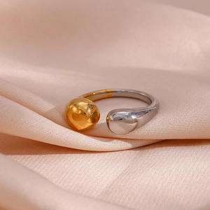 Macro shot of two-tone open ring with gold bead and silver teardrop on pink silk fabric