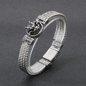 Close-up of vintage punk dragon head disc on a woven stainless steel keel chain bracelet