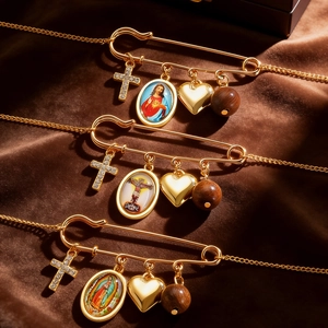 Detail of gold safety pins with cross, religious medal, heart, and wood bead pendants