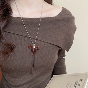Close-up of brown velvet bow necklace with zircon pendant on a model in knitwear