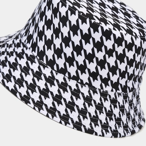 Dettaglio ravvicinato del motivo pied de poule e delle cuciture di un cappello a secchiello