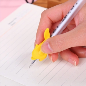 Yellow dolphin-shaped silicone pencil grip on a pen for writing posture correction