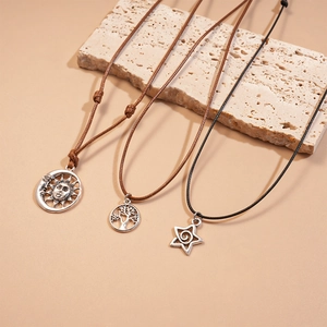 Close-up of three retro sun, moon, and tree of life pendants on woven wax cords