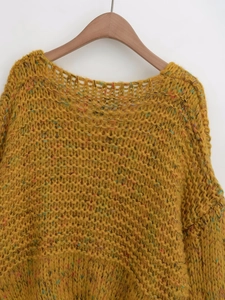 Close-up of yellow chunky knit sweater with colorful speckled yarn on a wooden hanger
